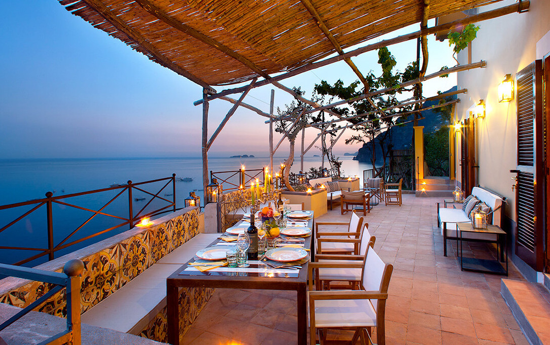 Un table dressée pour le dîner sous un auvent face à la mer - Grazie Gigi